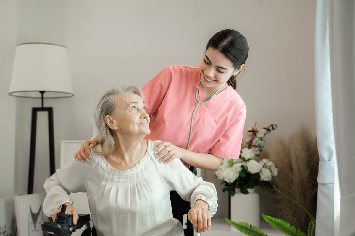 Cuidadora sonriendo junto a una mujer mayor en el salón de su casa