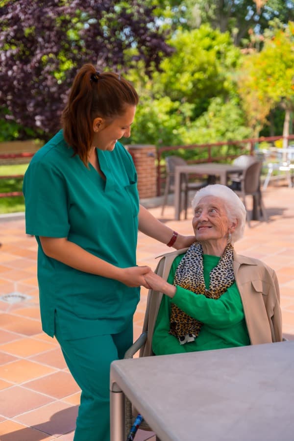 Cuidadora cogiendo de la mano a una mujer mayor en el jardín