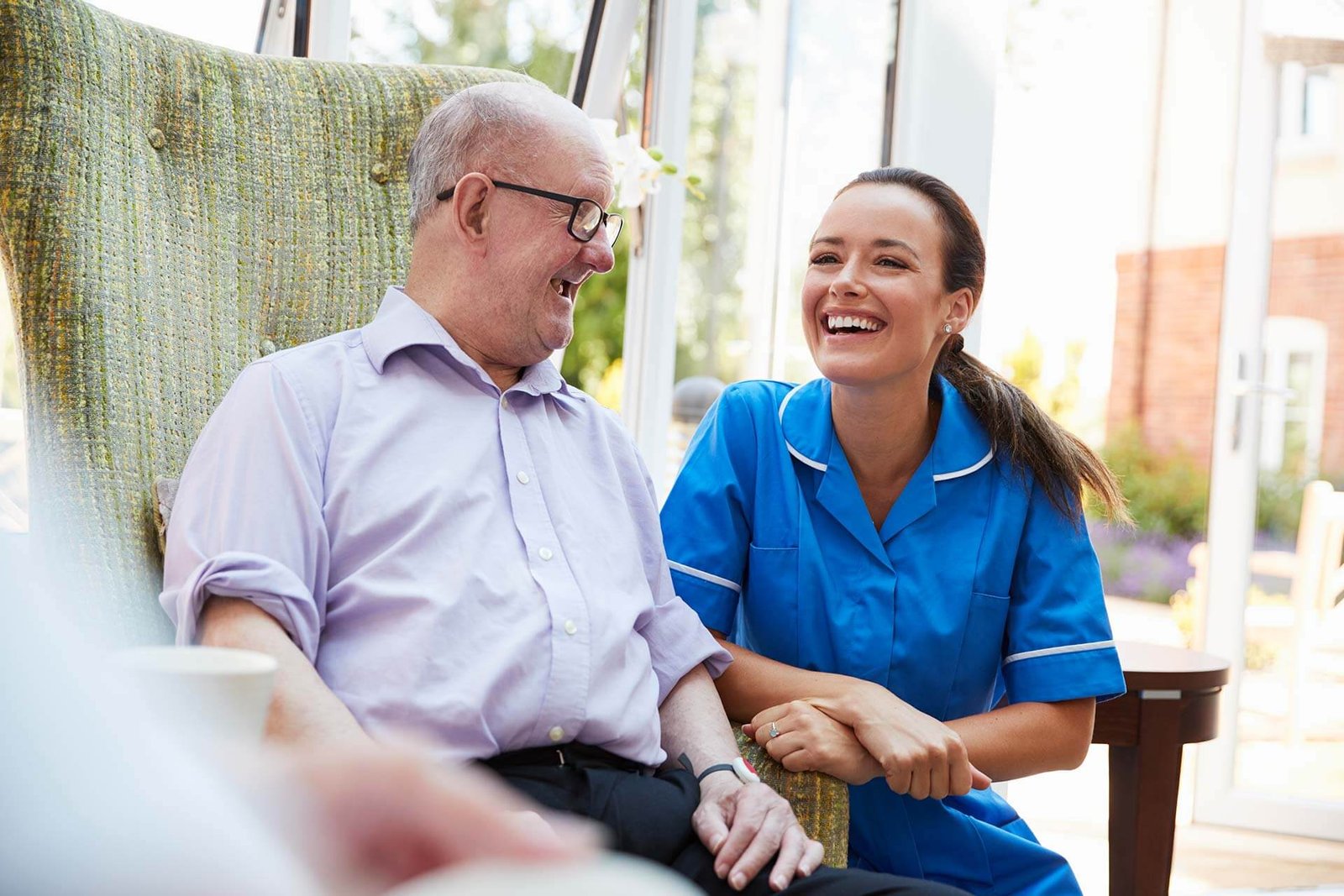 cuidadoras a domicilio en Mataró 12 senior man sitting in chair and talking with nurse